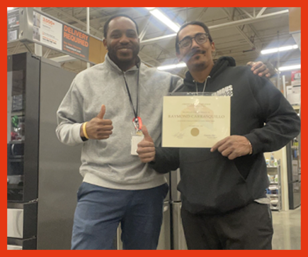 Two men smile at the camera, one holds a certificate